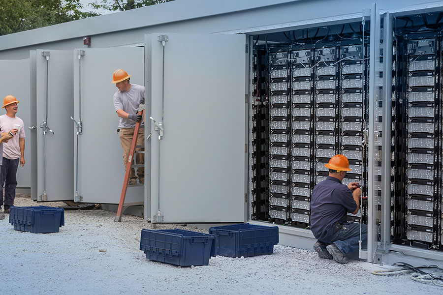 Engineers connecting energy storage batteries for back up power to an electric power plant